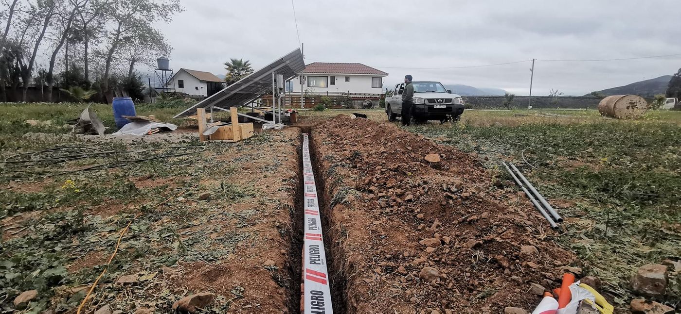 Zanja abierta para canalización subterránea junto al sistema fotovoltaico, con cinta de señalización preventiva identificando el recorrido