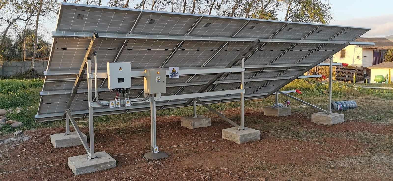 Sistema fotovoltaico on-grid terminado sobre estructura metálica a nivel de terreno, con inversor y tableros eléctricos montados en la estructura